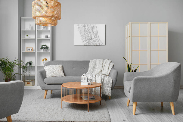 Interior de la elegante sala de estar con sofá gris, sillones y mesa de centro de madera - Foto, imagen