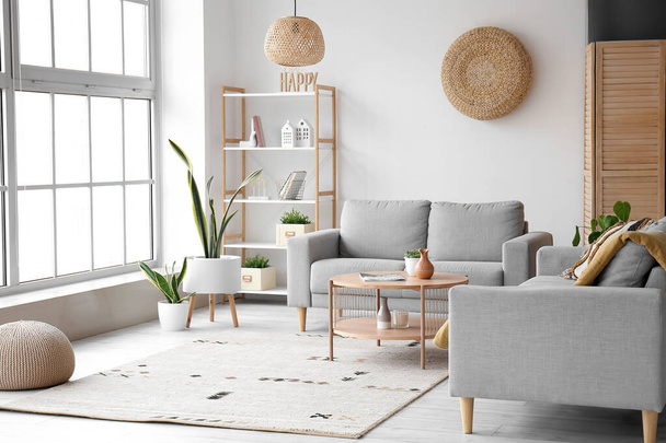 Интерьер светлой гостиной с серыми диванами и деревянным журнальным столиком - Фото, изображение
