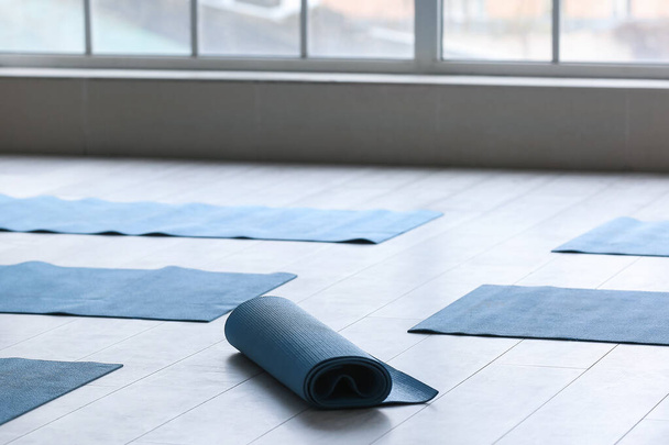 Tapis de yoga sur le sol près de la fenêtre dans la salle de gym - Photo, image
