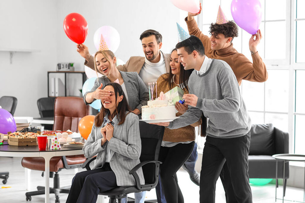 ビジネスの人々のグループは、オフィスでパーティーで誕生日ケーキと彼らの同僚を驚かせます - 写真・画像