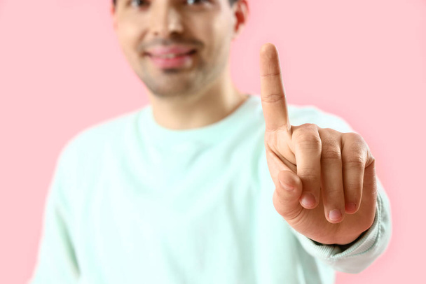 Young man using virtual screen on pink background, closeup - Photo, Image