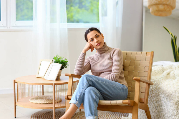 Mujer joven reflexiva en sillón en casa - Foto, Imagen