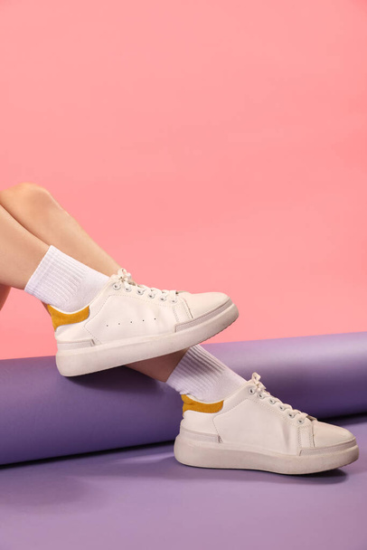 Female legs in stylish sneakers and socks on color background - Fotografie, Obrázek