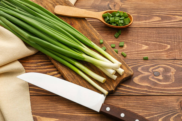 Board with fresh green onion on wooden background - Foto, Imagem