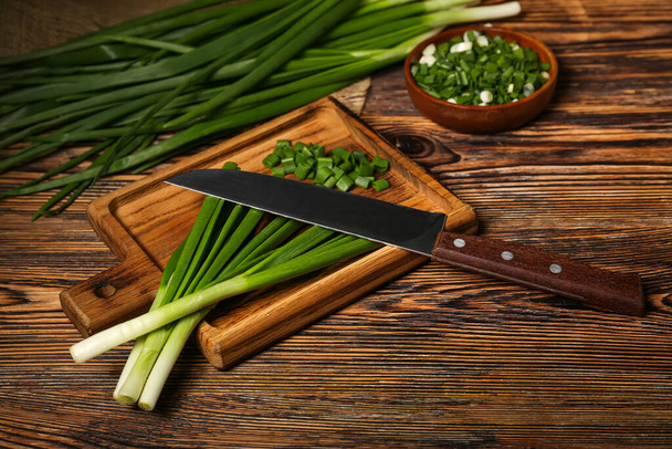 Board with fresh green onion on wooden background - Foto, Bild