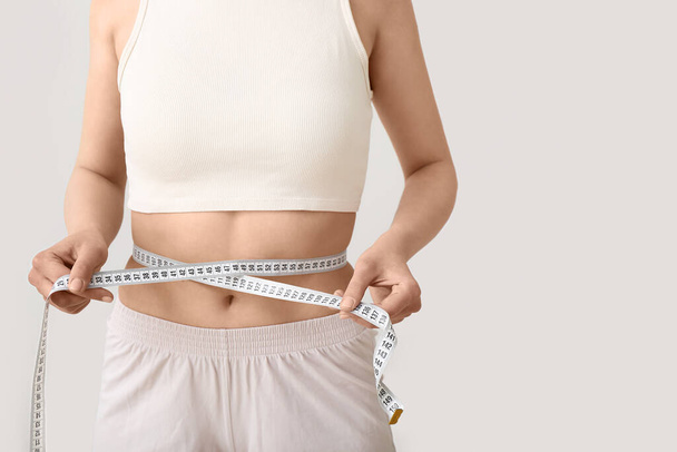 Young woman with measuring tape on white background. Diet concept - Φωτογραφία, εικόνα