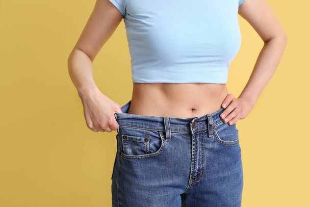 Junge Frau in lockeren Jeans auf beigem Hintergrund. Ernährungskonzept - Foto, Bild
