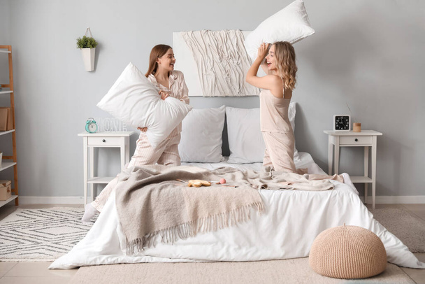 Küçük kız kardeşler yatak odasında yastık kavgası yapıyor. - Fotoğraf, Görsel