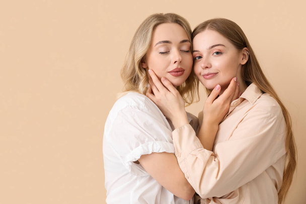 Young sisters hugging on beige background - 写真・画像