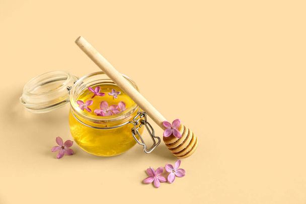 Frasco de mel e flores lilás em fundo bege - Foto, Imagem