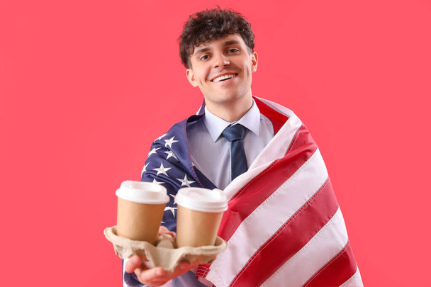 Männlicher Geschäftsmann mit USA-Flagge und Kaffeetassen auf rotem Hintergrund - Foto, Bild