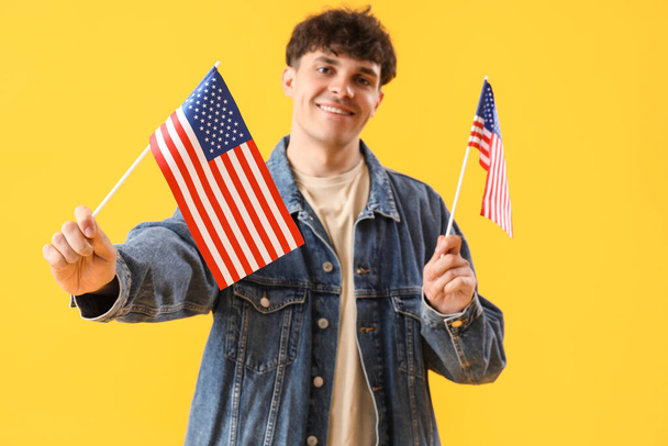 Young man with USA flags on yellow background - Zdjęcie, obraz