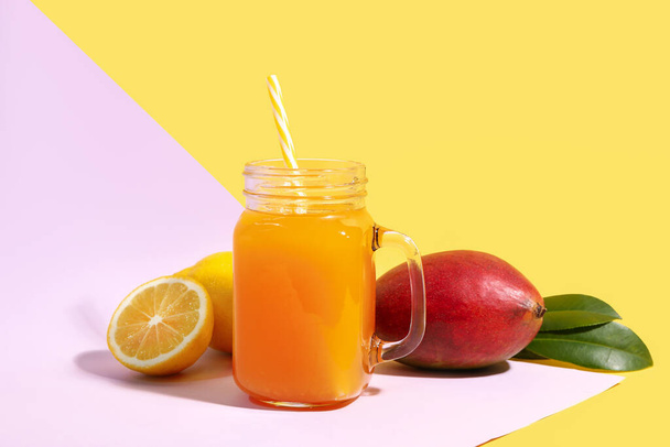 Mason jar of fresh mango smoothie and lemon on color background - Фото, зображення
