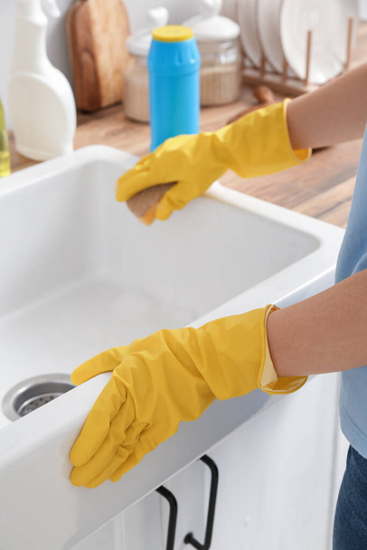Woman cleaning sink with sponge in kitchen, closeup - Fotoğraf, Görsel