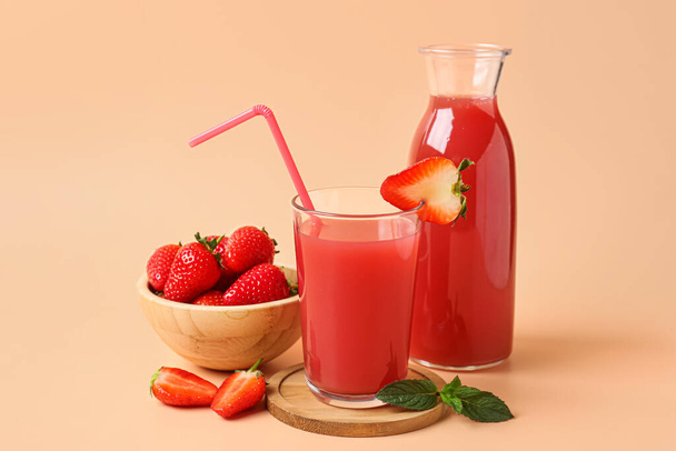 Bottle and glass of tasty strawberry juice on orange background - Photo, image