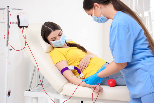 Жіноча медсестра бере кров від молодого донора в клініці
 - Фото, зображення