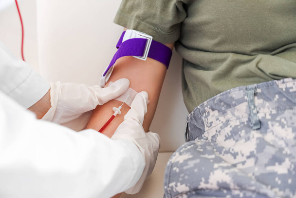 Γιατρός παίρνει αίμα από γυναίκα στρατιώτη στην κλινική, κοντινό πλάνο - Φωτογραφία, εικόνα
