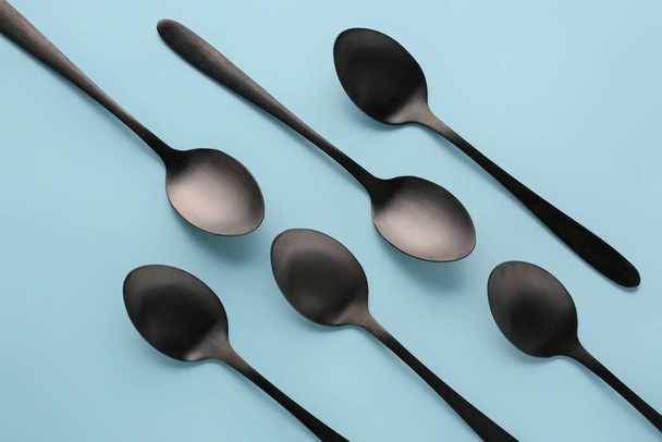 Black spoons on blue background - Foto, Imagen