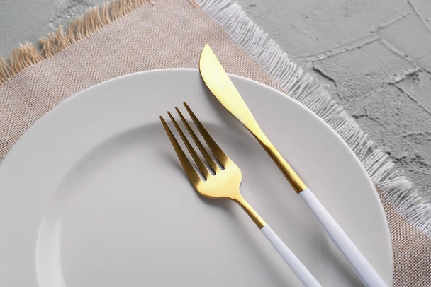 Пластины с золотой вилкой, ножом и кухонной салфеткой на зеленом фоне гранжа - Фото, изображение