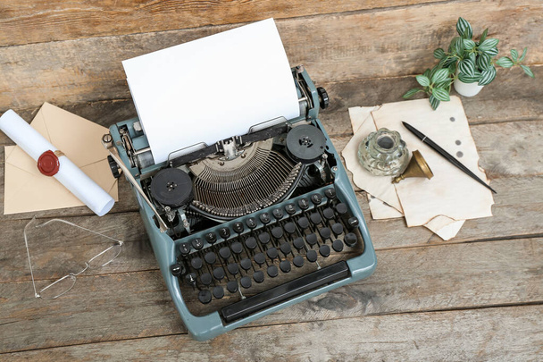 Vintage-Schreibmaschine, Tintenfass, Brille und Schriftrolle mit Wachssiegelstempel auf braunem Holzgrund - Foto, Bild
