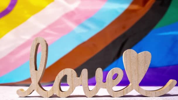 Zoom sur le mot en bois love with heart romance on Rainbow Drapeau LGBTQIA en soie. Carte de voeux pour la Saint Valentin. Symbole du mois de la fierté LGBTQ. Egalité des droits. Paix et liberté. Appui - Séquence, vidéo