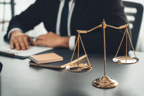 Εστίαση λαμπερή χρυσή ισορροπημένη κλίμακα σε θολή φόντο του δικηγόρου που εργάζεται στο γραφείο του στο γραφείο δικηγορικό γραφείο. Ισορροπία κλίμακας για δίκαιη και ισότιμη κρίση από νομοθέτη και δικηγόρο. Ισορροπία - Φωτογραφία, εικόνα