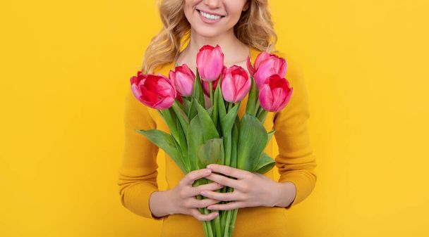 usmívající se mladá dívka s jarní tulipán květiny na žlutém pozadí. - Fotografie, Obrázek
