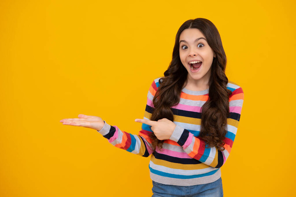 Teenager child pointing to the side with a finger to present a product or idea. Teen girl in casual outfit pointing empty space. Amazed teenager. Excited teen girl - Fotoğraf, Görsel