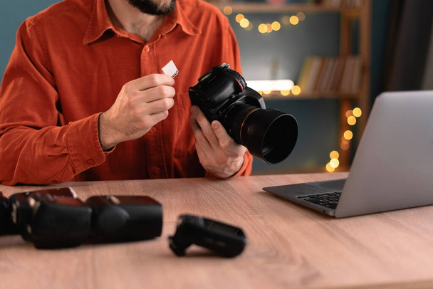 Fotógrafo, jornalista ou criador criativo copiando fotos de sua câmera para o laptop que trabalha em casa. Mão com cartão SD. processo criativo de fotógrafo freelance. Close-up - Foto, Imagem