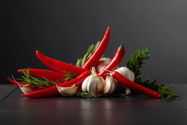 Rode hete chili pepers, knoflook en rozemarijn op een zwarte achtergrond.Kopieer ruimte. - Foto, afbeelding