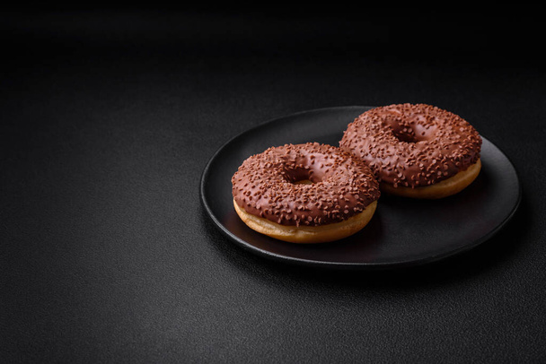 Delicious chocolate glazed donut sprinkled with chocolate chips on a dark concrete background - Valokuva, kuva