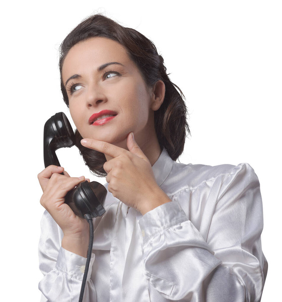 Pensive vintage secretary on the phone with hand on chin - Photo, image