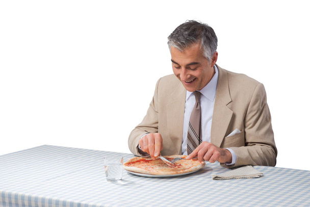Smiling elegant businessman having a pizza during his lunch break - Photo, Image