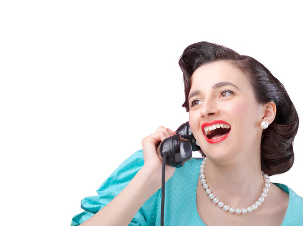 Cheerful vintage style elegant woman having an exciting phone call and gossiping with her friend, she is holding the receiver and smiling - Zdjęcie, obraz
