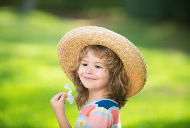 Retrato infantil caucásico de cerca. Niños en sombrero de paja con plumeria flor - Foto, imagen