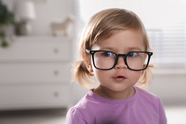 Cute little girl in glasses at home. Space for text - Foto, afbeelding