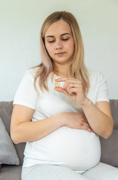 Hamile kadın omega üç içiyor. Seçici odaklanma. Beyaz. - Fotoğraf, Görsel