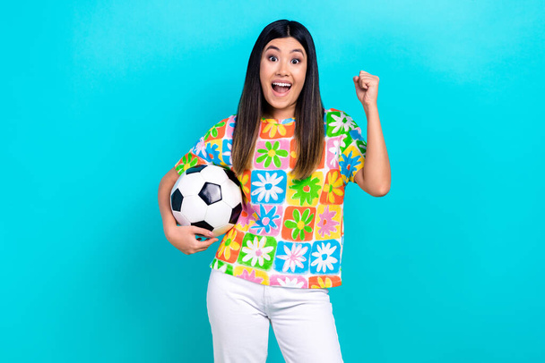 Photo of crazy young chinese woman wear flowers print shirt fist up hold football sphere win match isolated on aquamarine color background. - Foto, Imagen