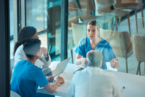 Medical team, doctors and meeting with a laptop for a discussion, planning or research at table. Men and women healthcare group talking about communication strategy, virus or surgery in a hospital. - 写真・画像