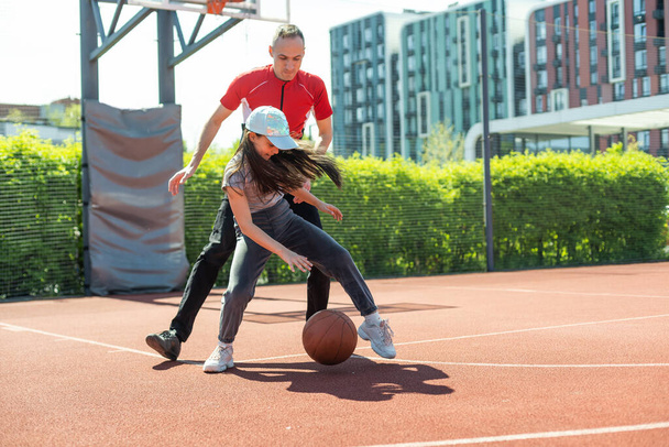 Happy father and teen daughter embracing and looking at camera outside at basketball court - Photo, Image