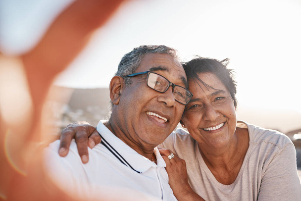 Selfie, romance and a senior couple on the beach together during summer for a retirement holiday or vacation. Portrait, smile or dating with an old husband and wife posing for a photograph by the sea. - Photo, Image