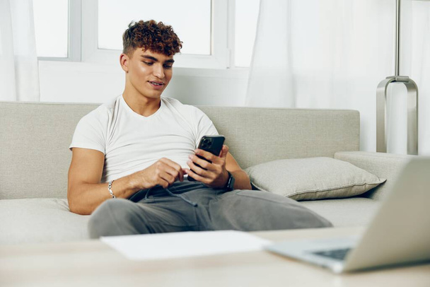セルオンラインライフスタイルの若い携帯電話の家を使用して男のインテリアカーリー テキストビジネスモックアップ技術ソファメッセージフリーランサー - 写真・画像