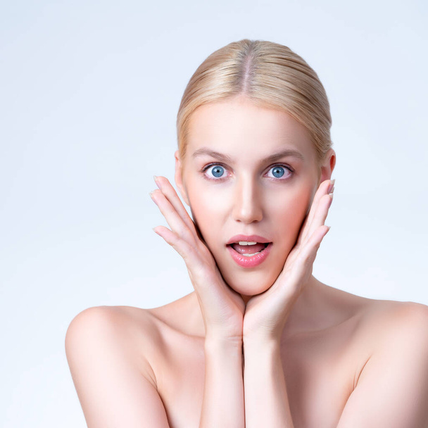 Personable beautiful woman with perfect smooth clean skin and natural soft makeup in isolated background. Hand gesture with expressive surprise facial expression for beauty care and spa concept. - 写真・画像