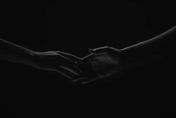 Two hands reaching toward. Helping hand outstretched for salvation on isolated black background. Close up of man and woman hand touch with fingers - Fotoğraf, Görsel