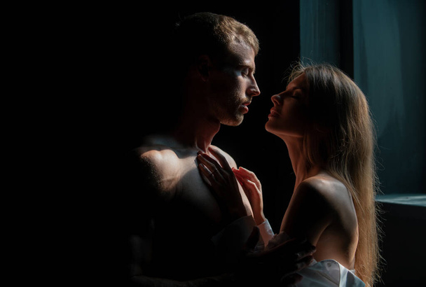 Close up face of sensual portrait of a sexy couple embracing while dating. Young couple in love in bedroom on black. The lovely coupl spends time together - Фото, зображення