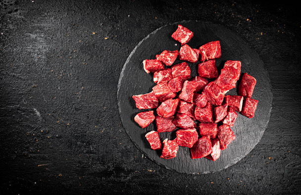Pieces of raw beef on a stone board. On a black background. High quality photo - Valokuva, kuva