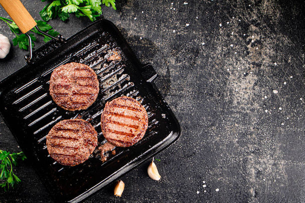 Grilled burger in a frying pan. On a black background. High quality photo - 写真・画像