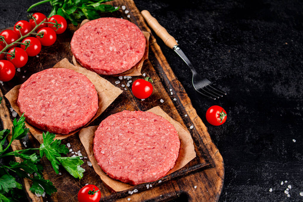 A raw burger on a tomato cutting board. On a black background. High quality photo - Foto, Imagem