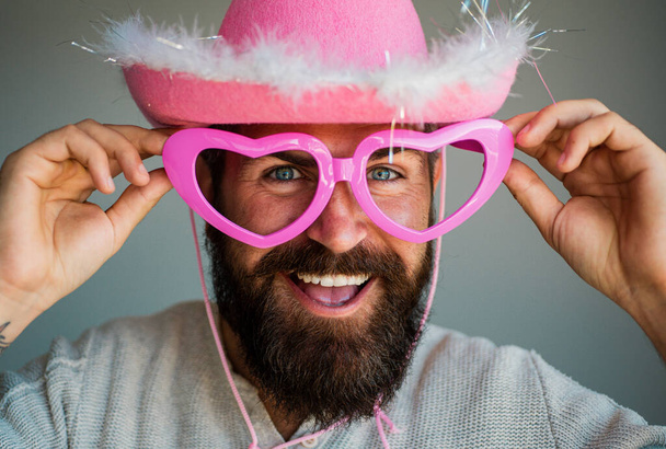 Bearded man in big glasses. Funny guy in big eyeglasses. Happy man with funny pink glasses. Handsome smiling young guy. Positive human facial expressions and emotions. Fun cowboy - Photo, image