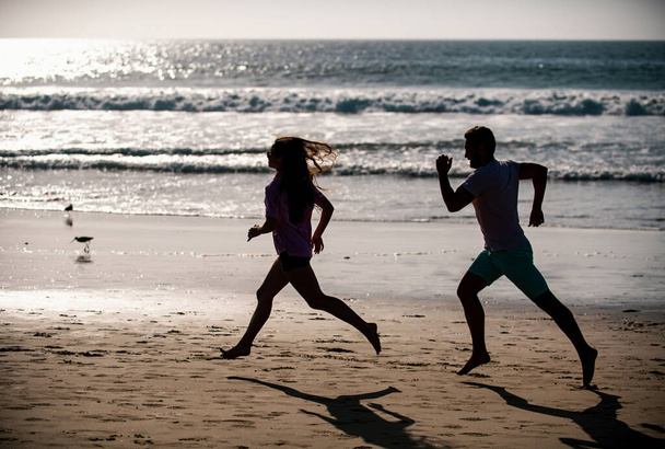 Sport and healthy lifestyle, friends jogging at sunset on the beach. Silhouette couple running on beach - Foto, Imagem